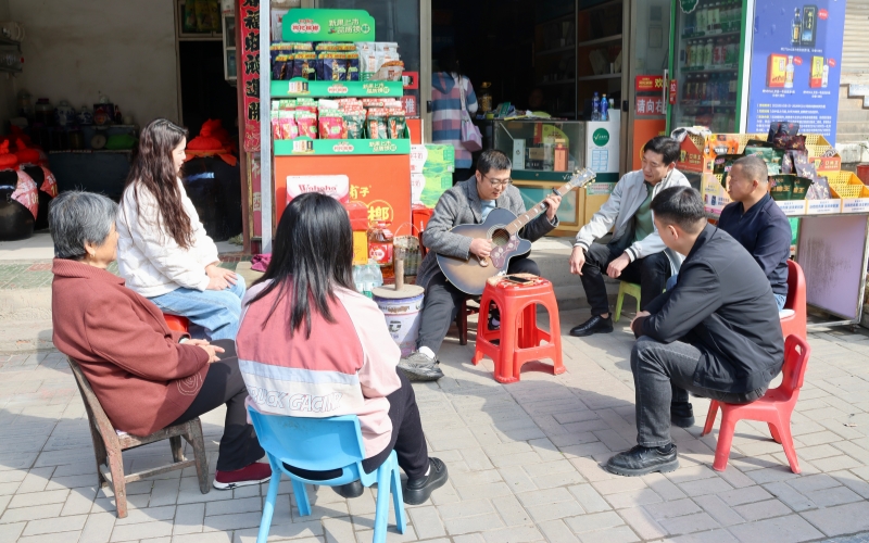 王童童在小店外弹奏吉他。