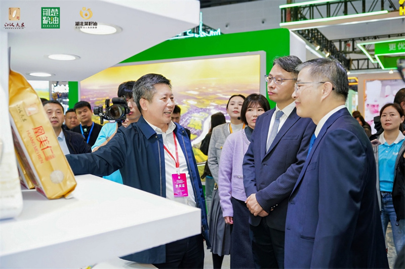 湖北省发展和改革委员会党组成员、湖北省粮食局党组书记、局长易俊东向国家粮食和物资储备局副局长陈军生(右一)介绍湖北“荆楚粮油”“江汉大米”“湖北菜籽油”三大优质粮油公用品牌