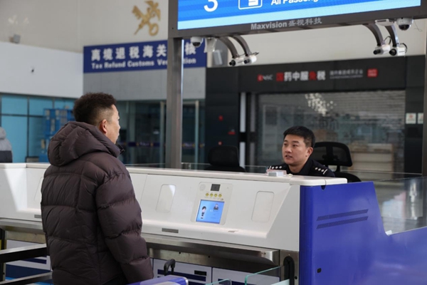 工作人员对出境旅客进行边防检查。牡丹江市委新闻中心供图