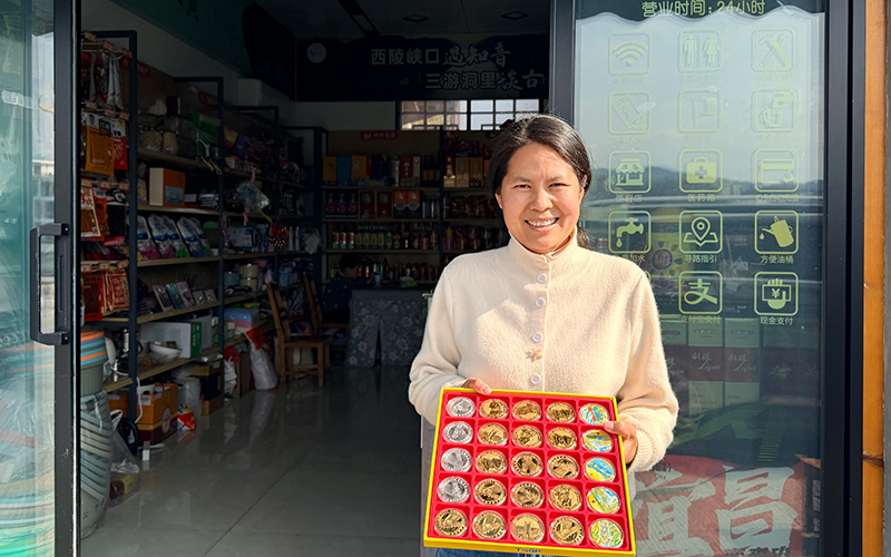 陈丽在店门口展示景区纪念币。